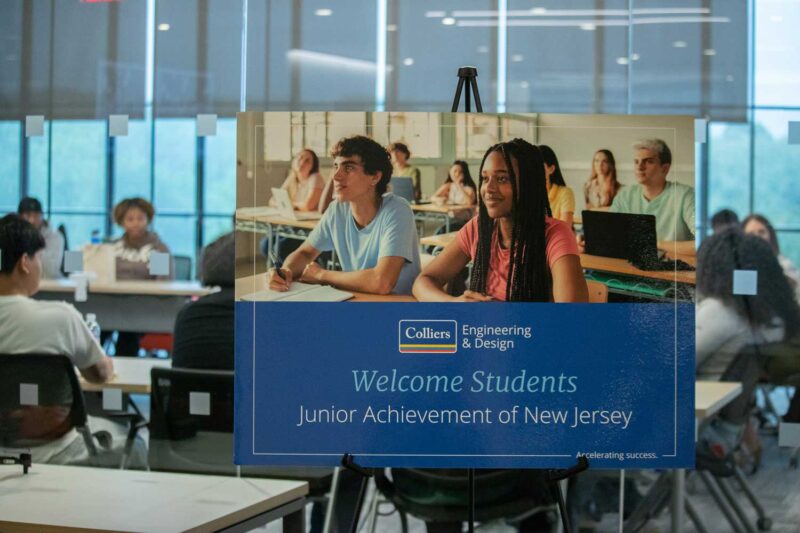 Sign that reads Welcome Students Junior Achievement in front of a classroom full of students
